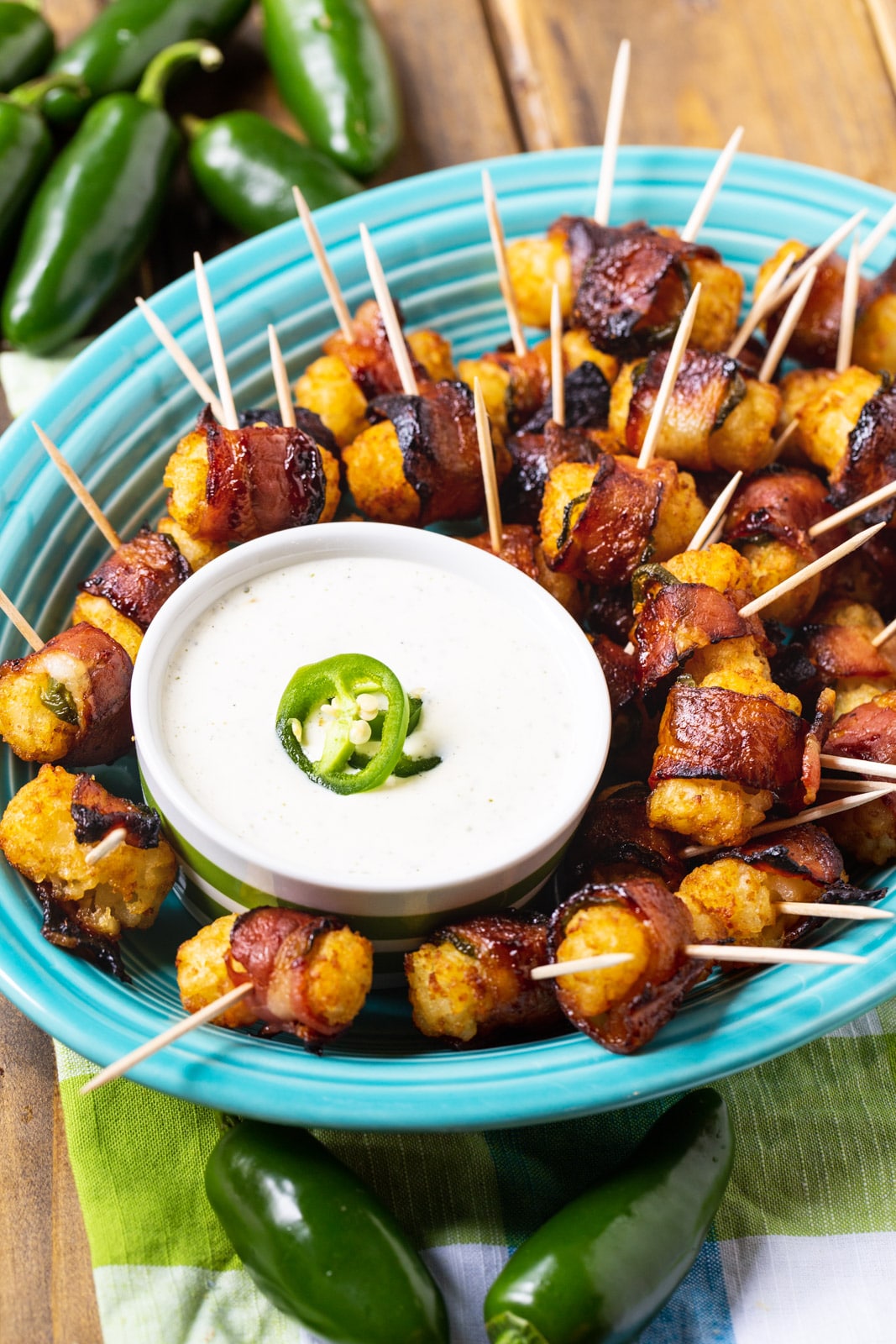 Bacon Wrapped Tater Tots on a blue serving plate with dippinf sauce.