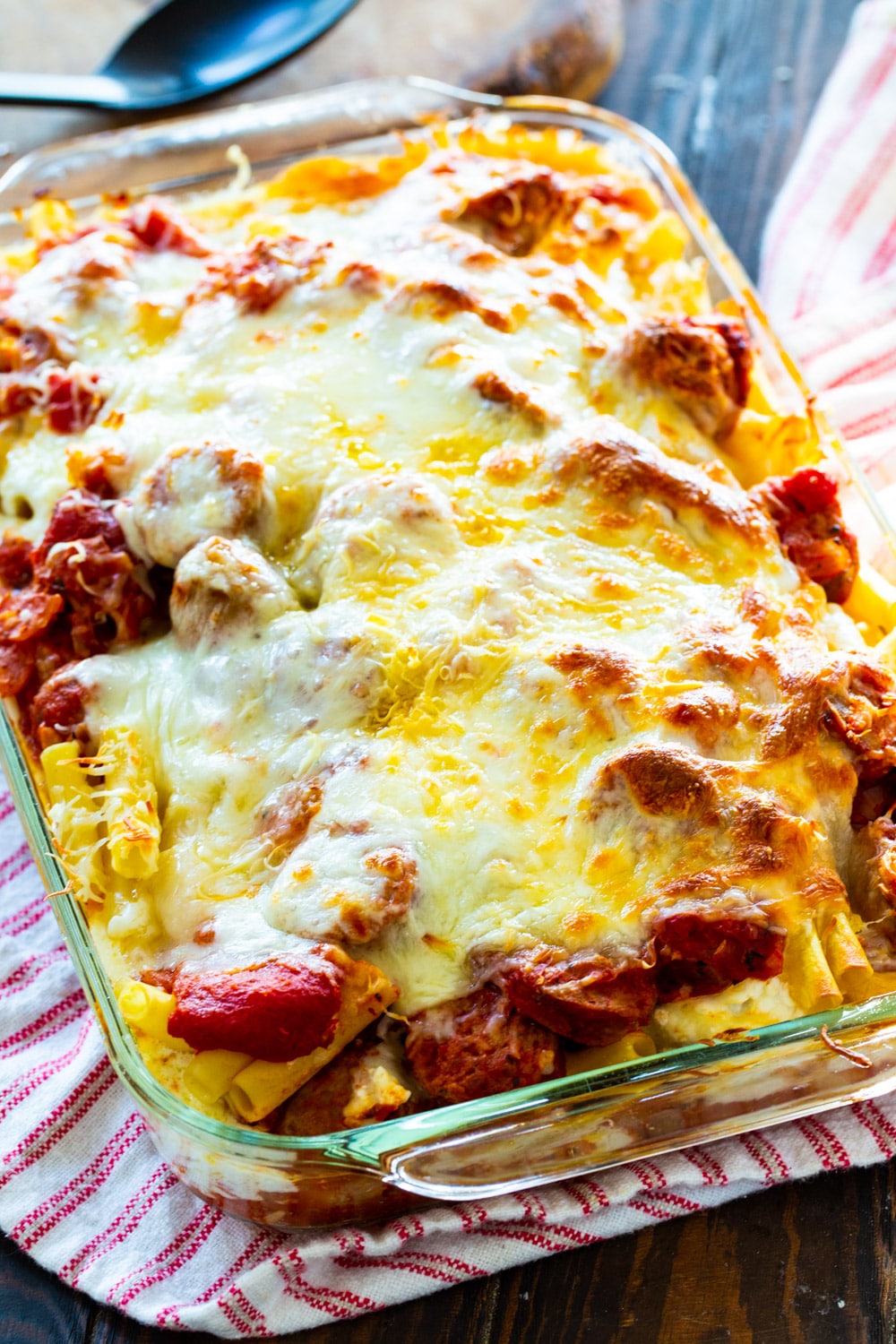 Baked ziti covered with melted cheese in baking dish.