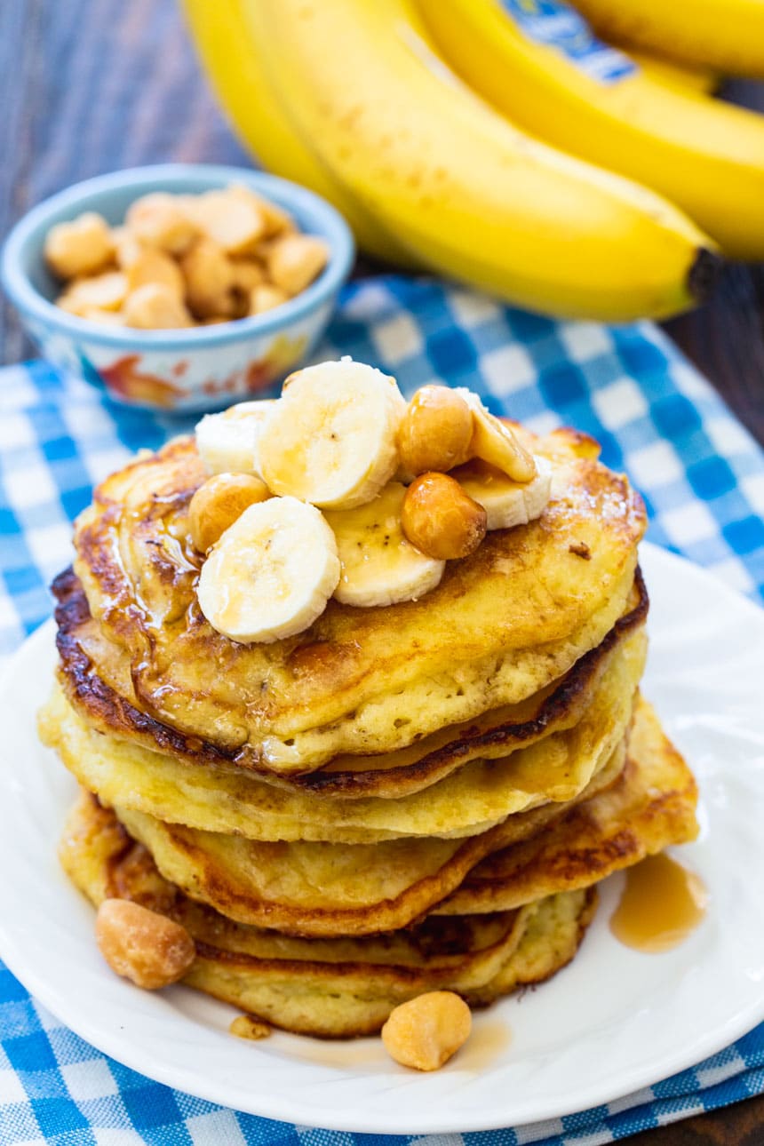 Banana Macadamia Nut Pancakes on a plate with bananas in background.