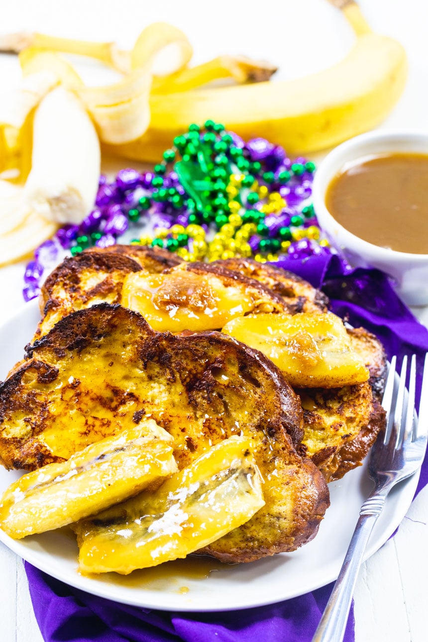 French Toast on white plate with beads and bananas in background.