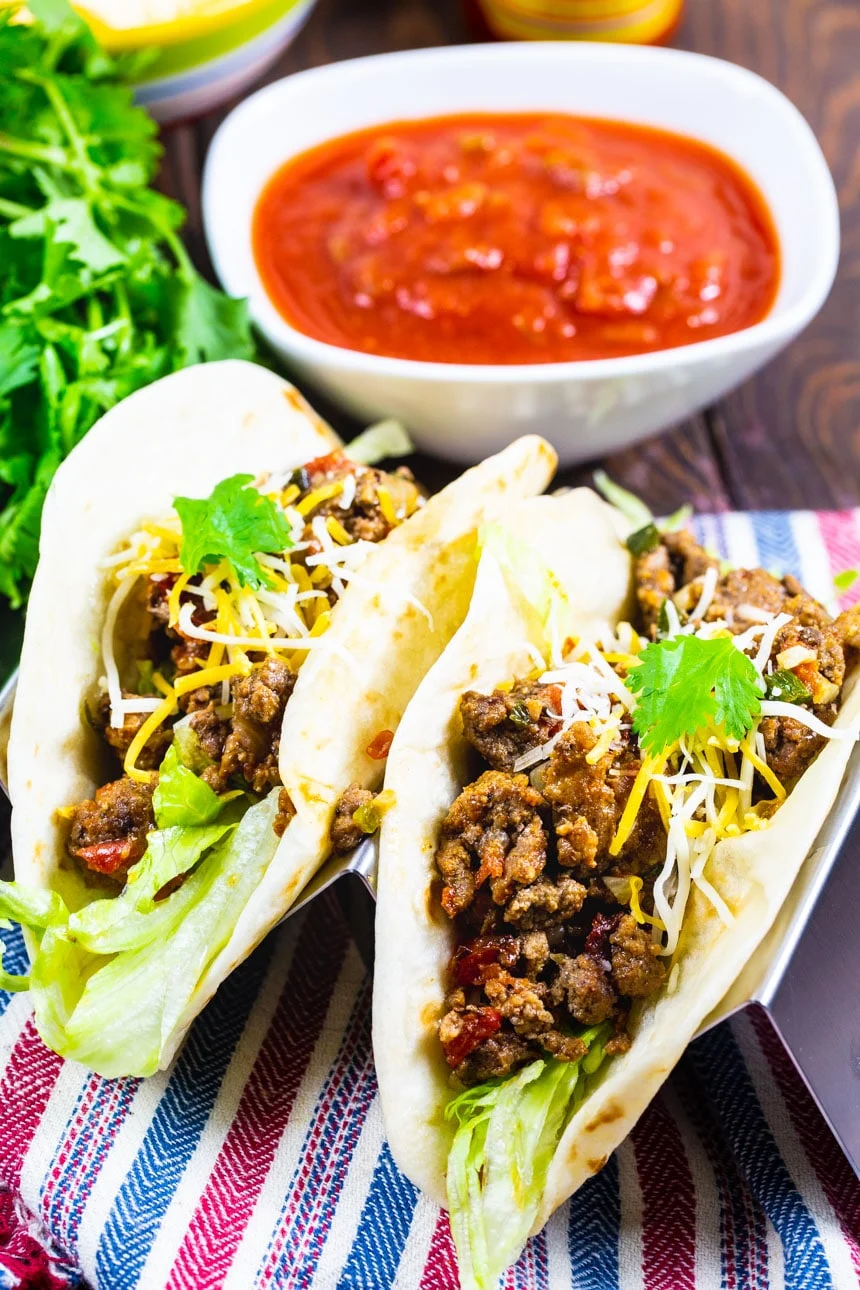 Two Tacos with Best Ever Taco Meat and salsa in background.