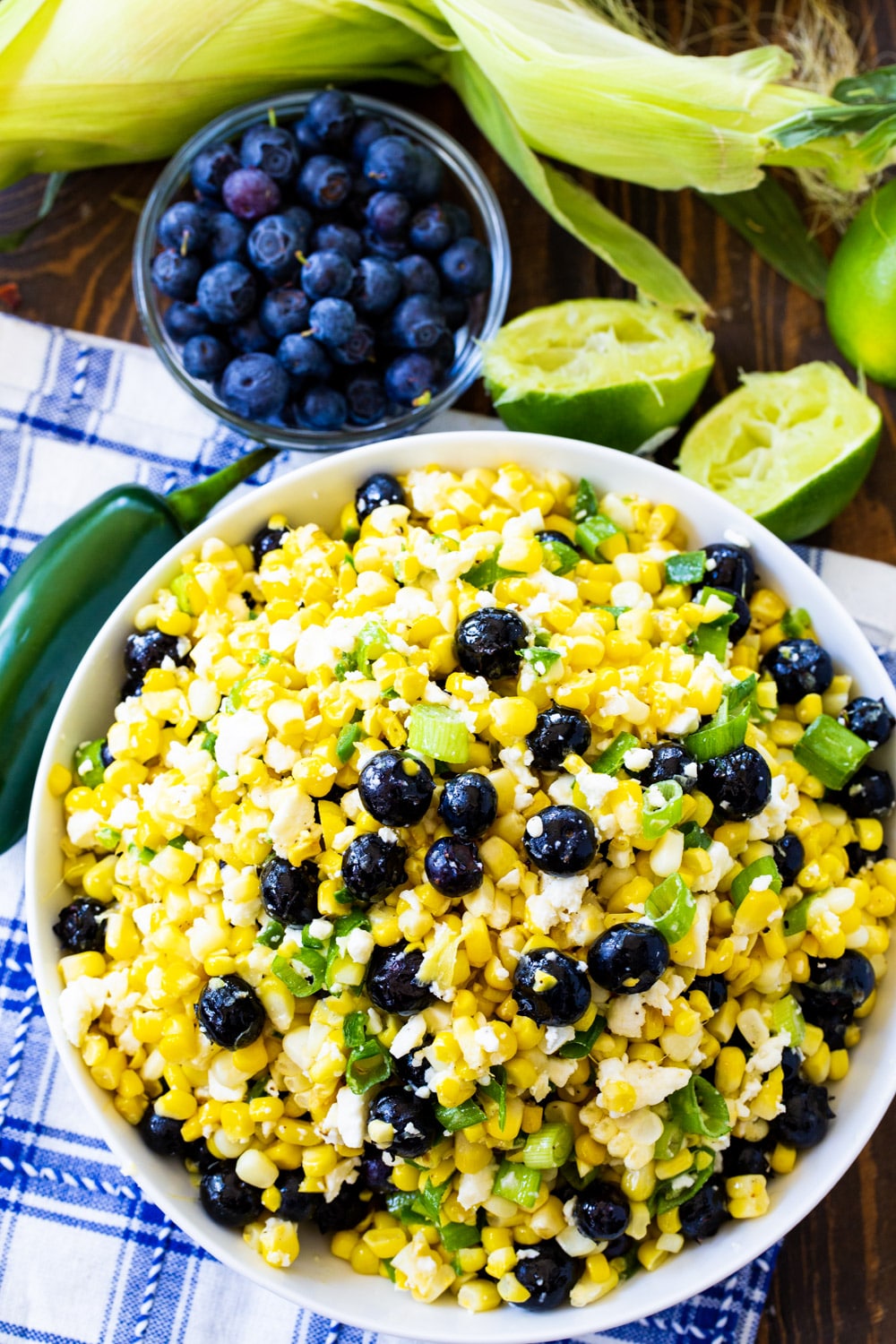 Blueberry, Corn and Feta Salad in a bowl surrounded by fresh blueberries and lime halves.