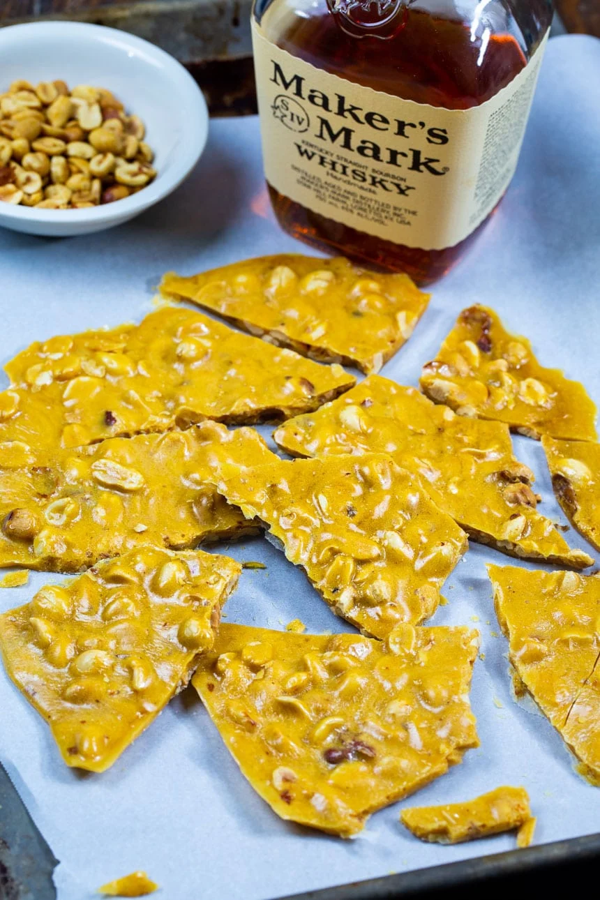 Peanut Brittle with bottle of bourbon and bowl of peanuts.