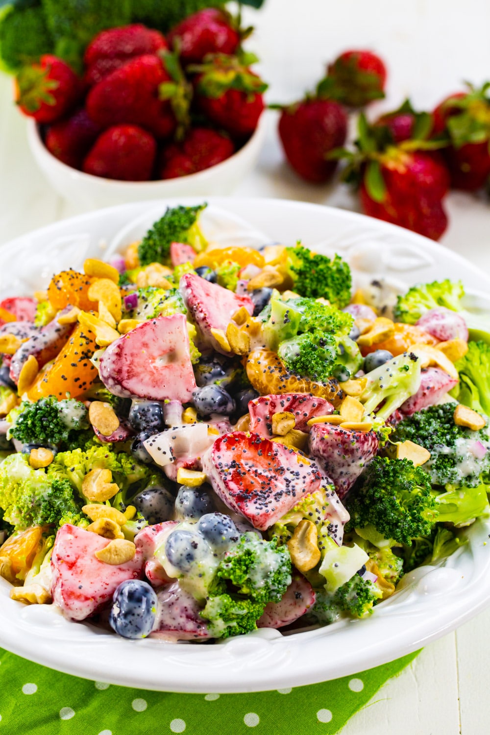 Broccoli Strawberry Salad in bowl with fresh strawberries in background.