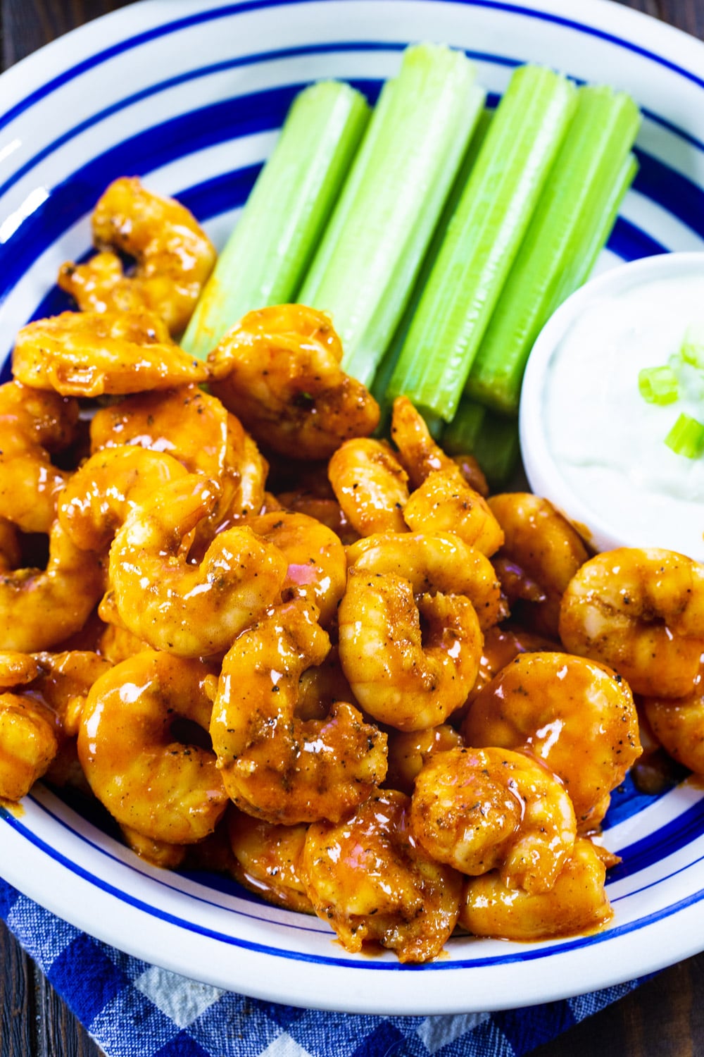 Shrimp coated in buffalo sauce on a blue and white plate.