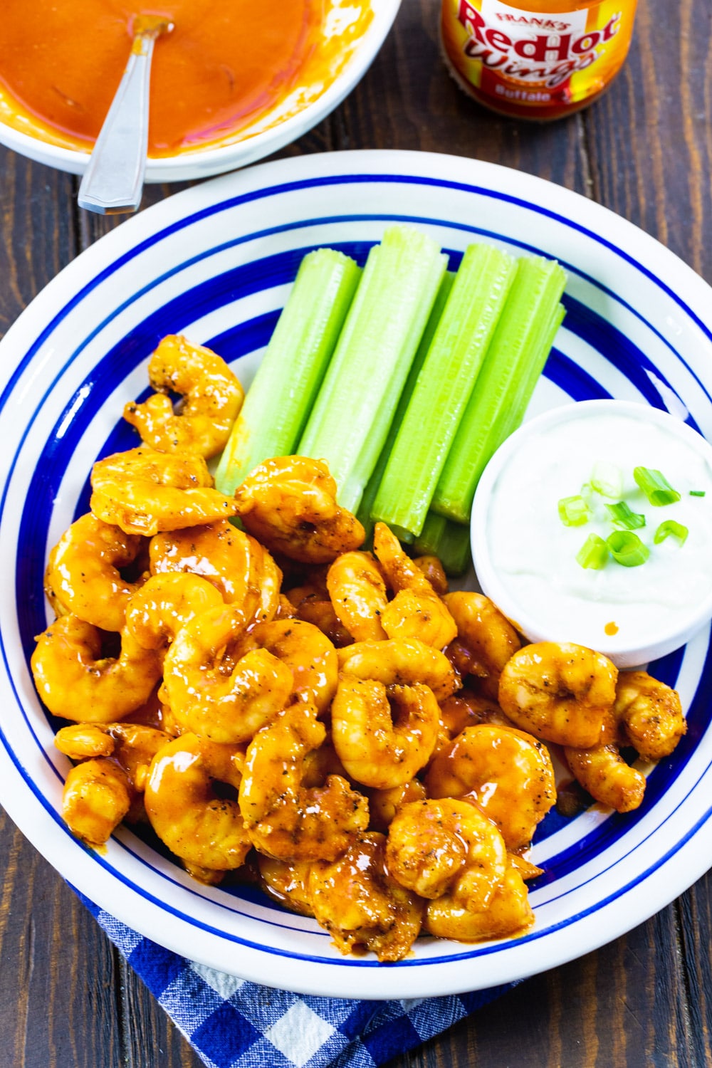 Buffalo Shrimp, celery, and blue cheese dressing on a plate.