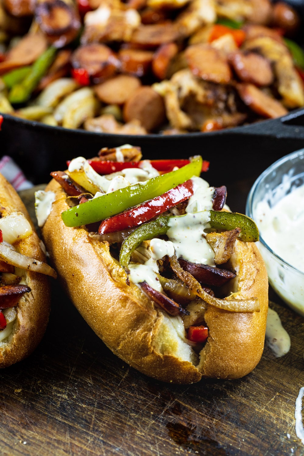 Cajun Chicken and Andouille Subs with skillet full of chicken and sausage filling in background.