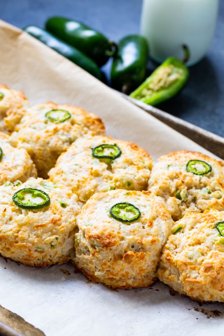 Biscuits on baking sheet with jalapenos in background.