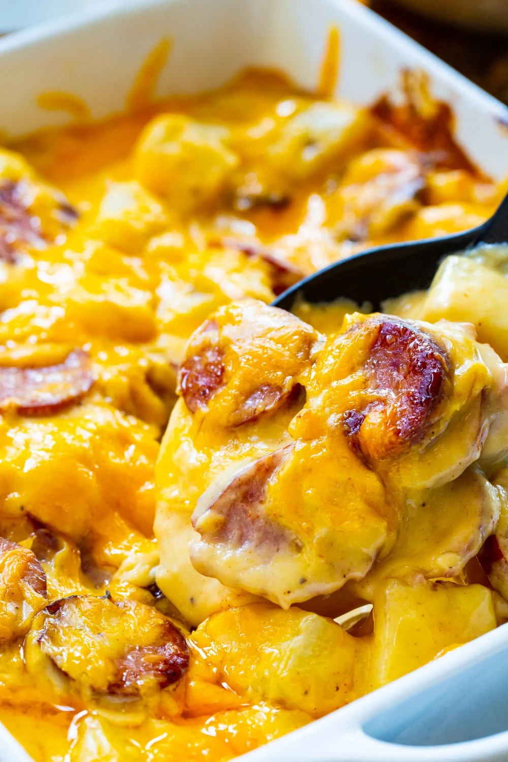 Spoon scooping up Cheesy Potatoes with Smoked Sausage