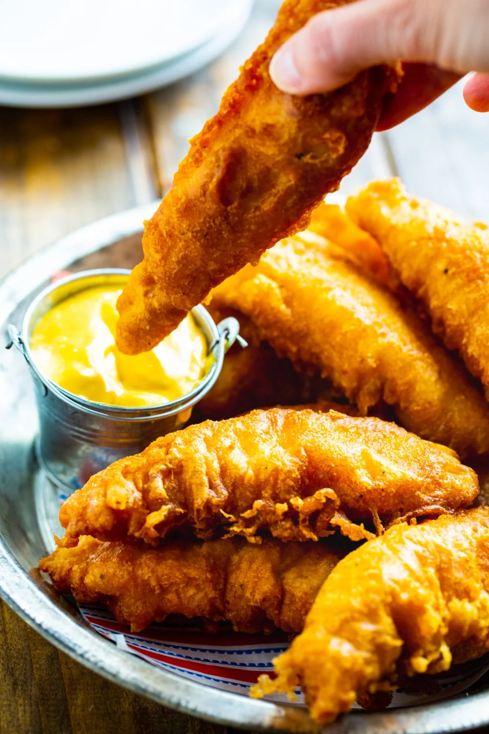 Chicken Crisper getting dipped in honey mustard.