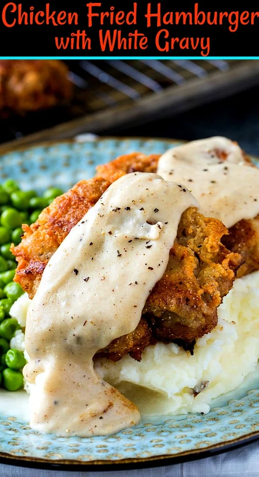 Two Hamuburger patties with gravy over mashed potatoes.