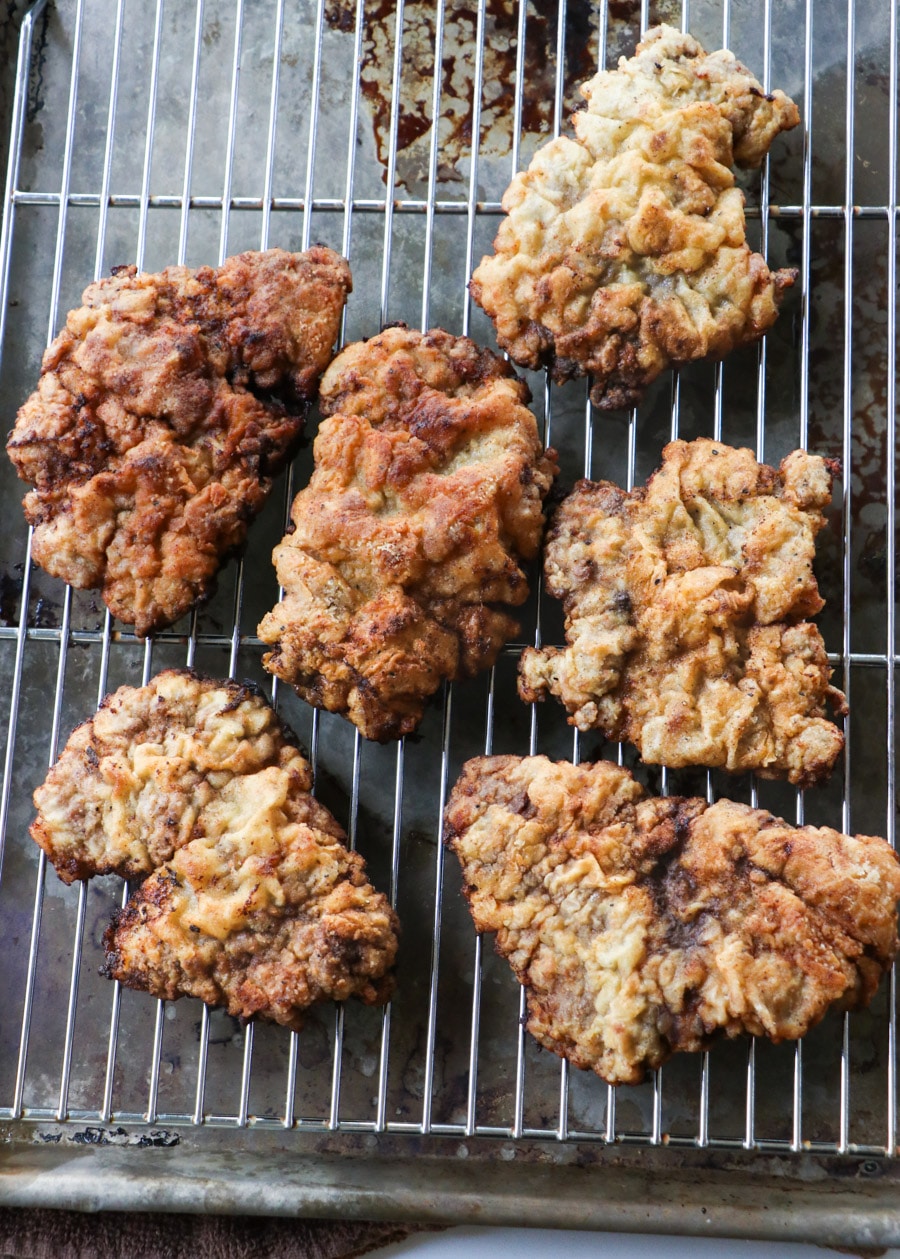 Cooked cubed steak pieces on a wire rack.