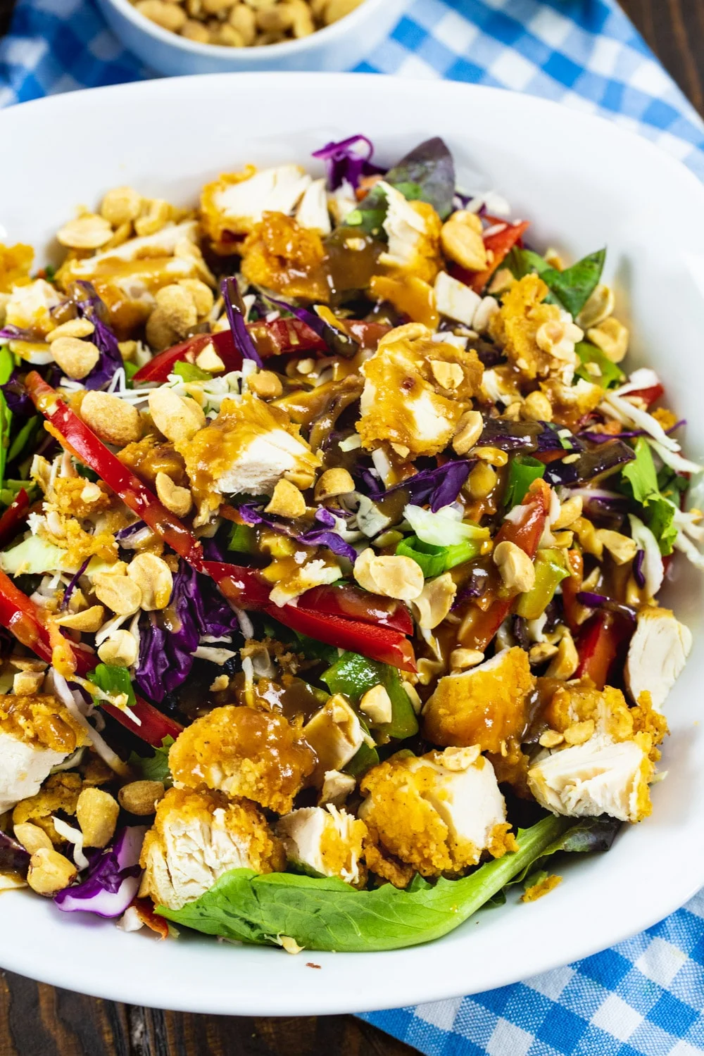 Chopped Salad with chicke tenders and peanut dressing in a large white bowl.