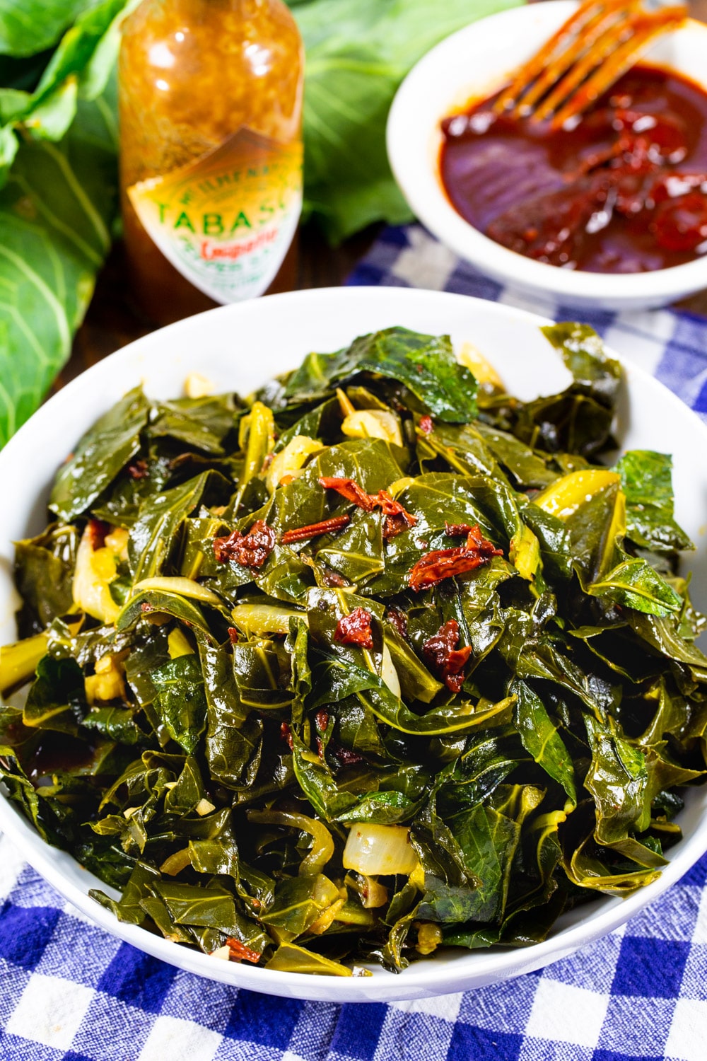 Chipotle Collard Greens in bowl with a bottle of hot sauce.