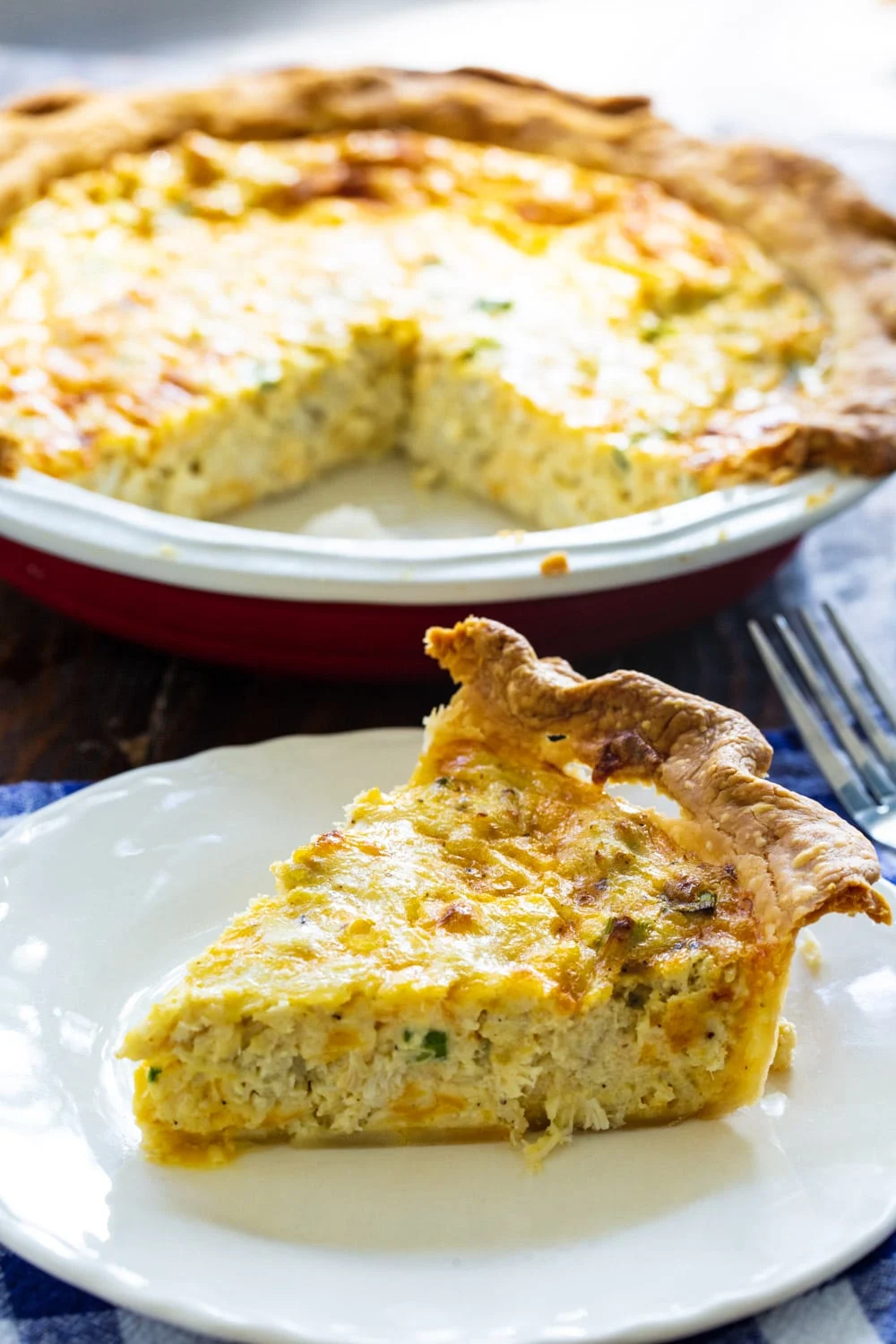 Slice of crab pie with the remaining pie in background.