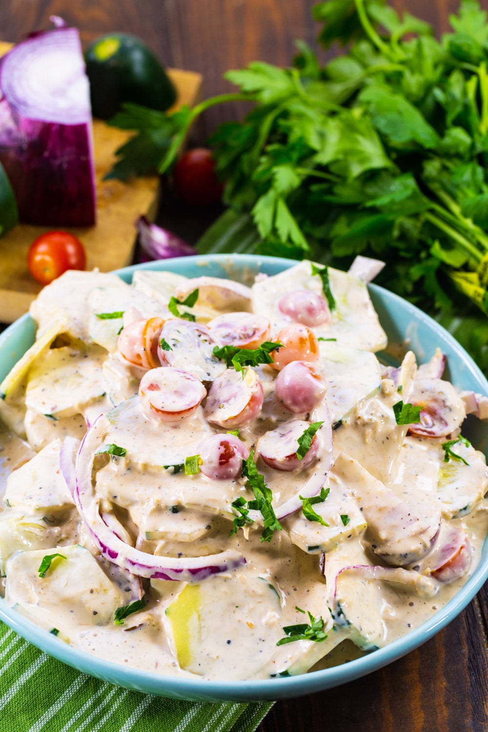 Creamy Italian Cucumber Salad in bowl with bunch of fresh parsley in background.