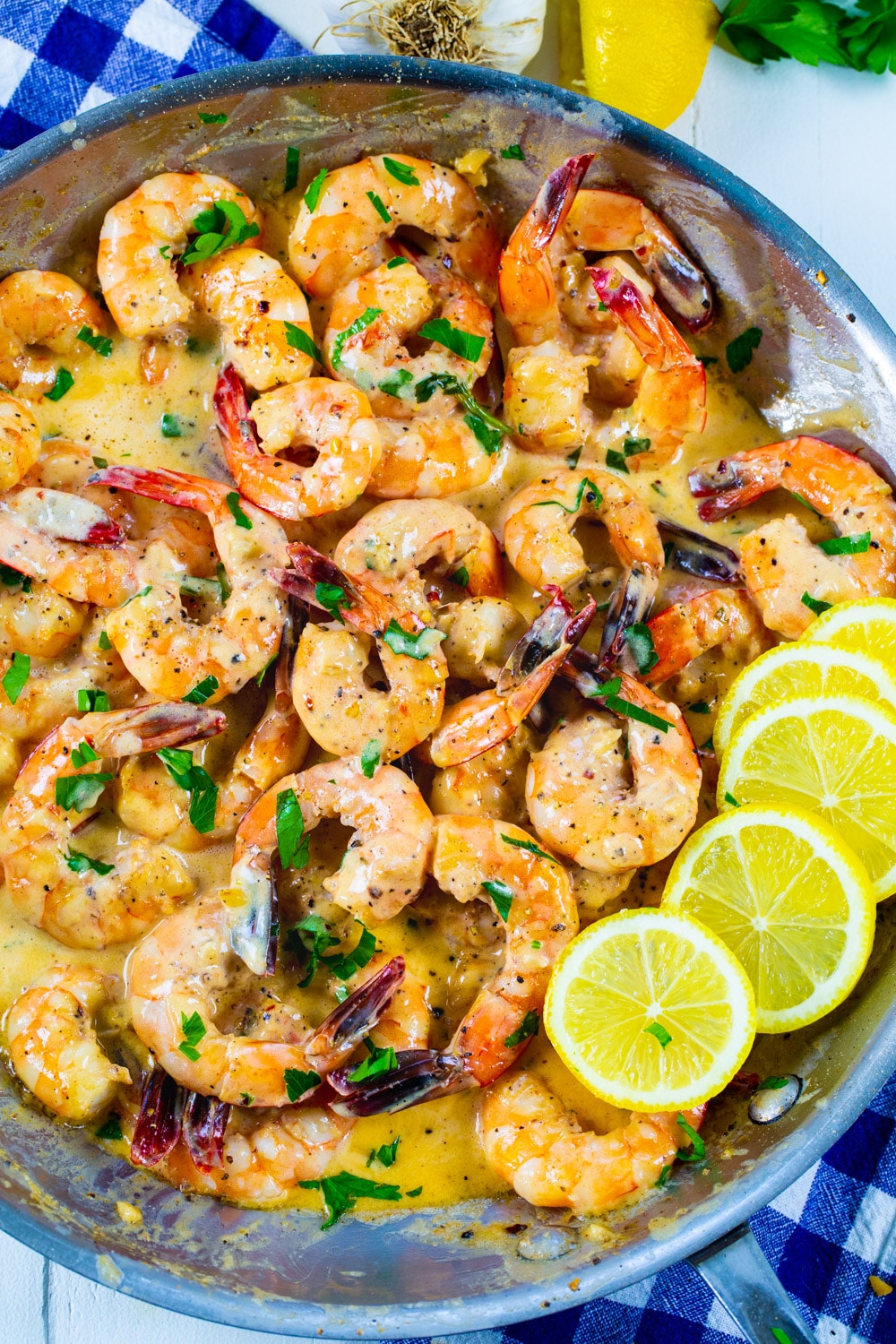 Cooked shrimp in a skillet with lemon slices.