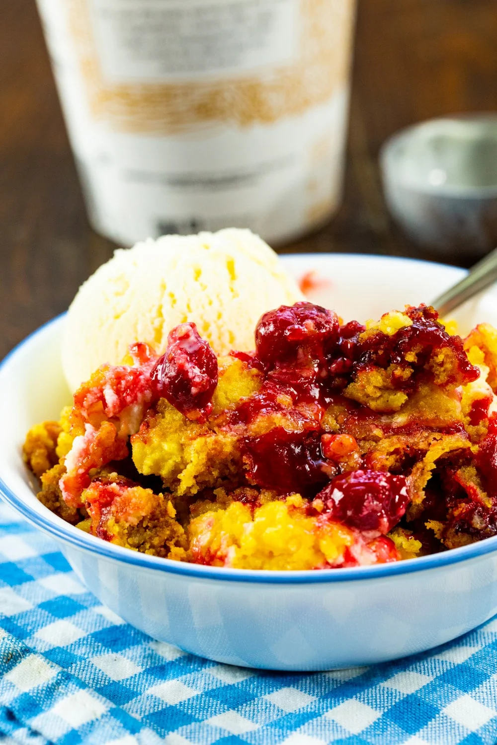 Crock Pot Cherries and Cream Dump Cake topped with vanilla ice cream in a bowl.