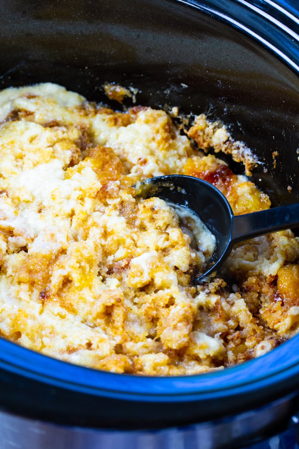 Spoon scooping Crock Pot Peaches and Cream Cake out of slow cooker.