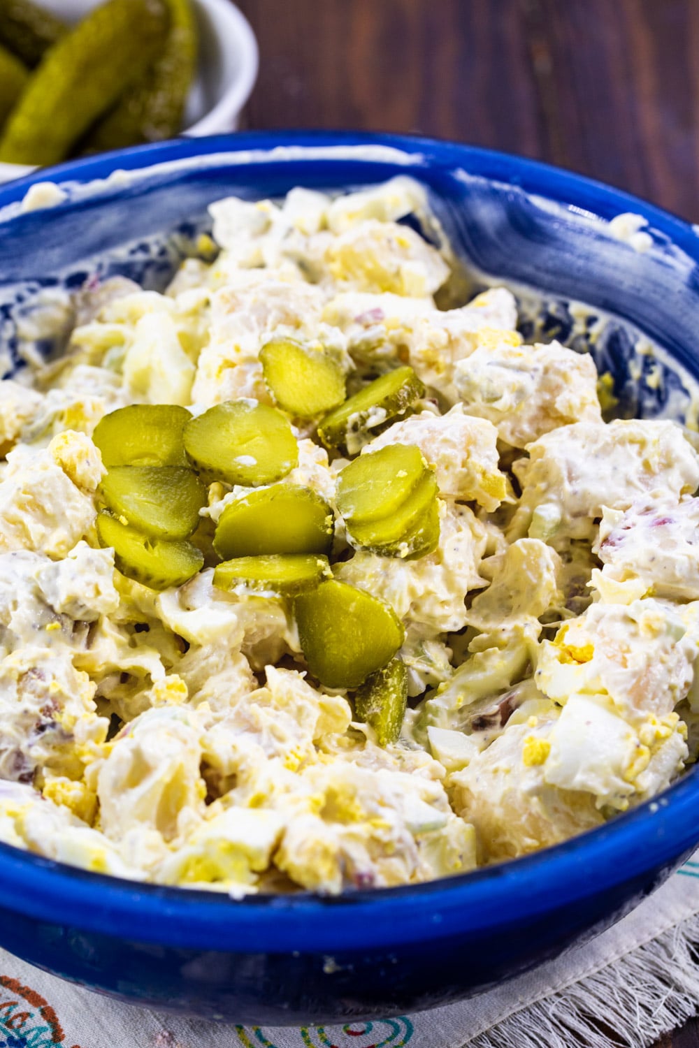 Potato salad topped with dill pickle slices.