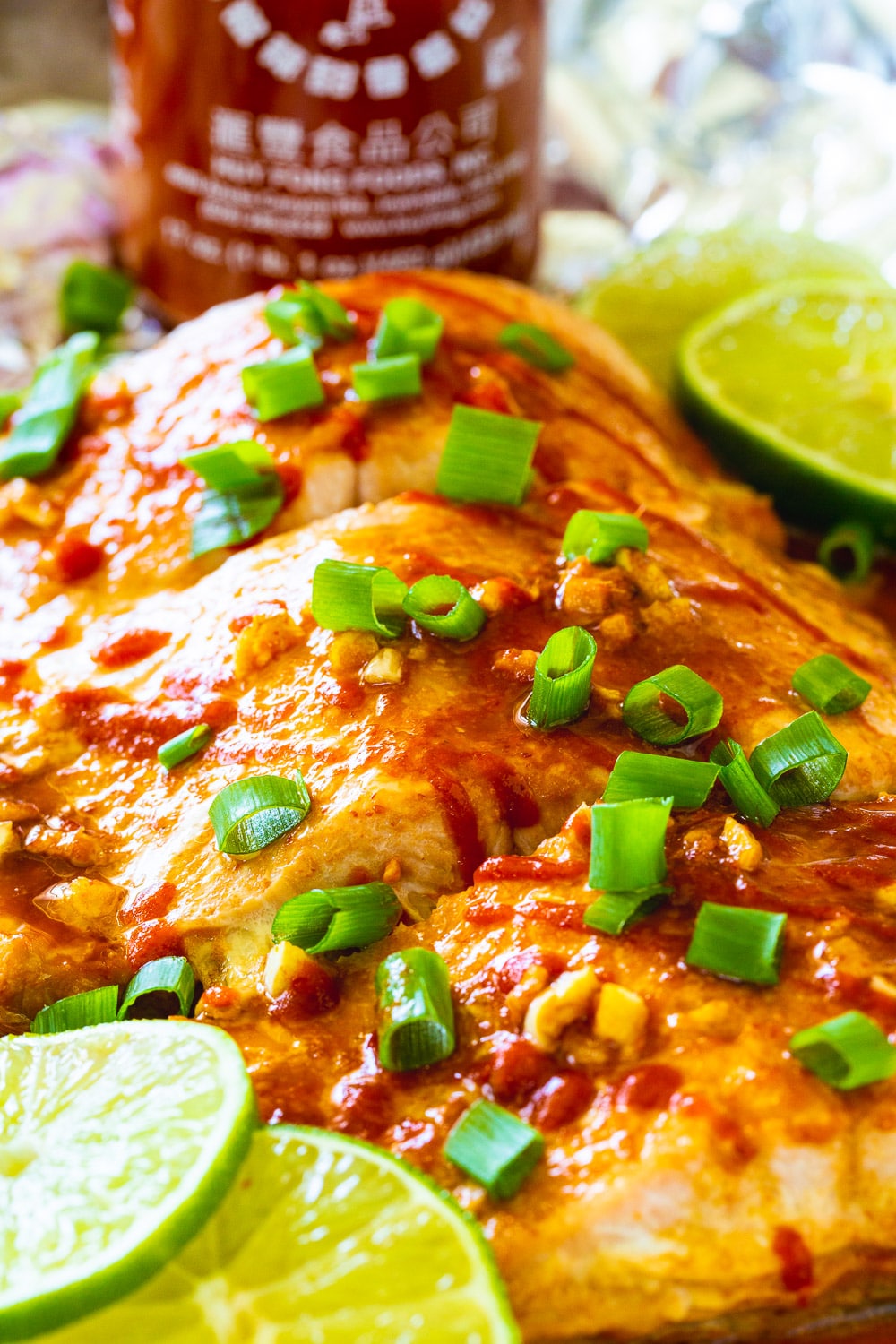 Baked Salmon with lime slices and bottle of Sriracha.