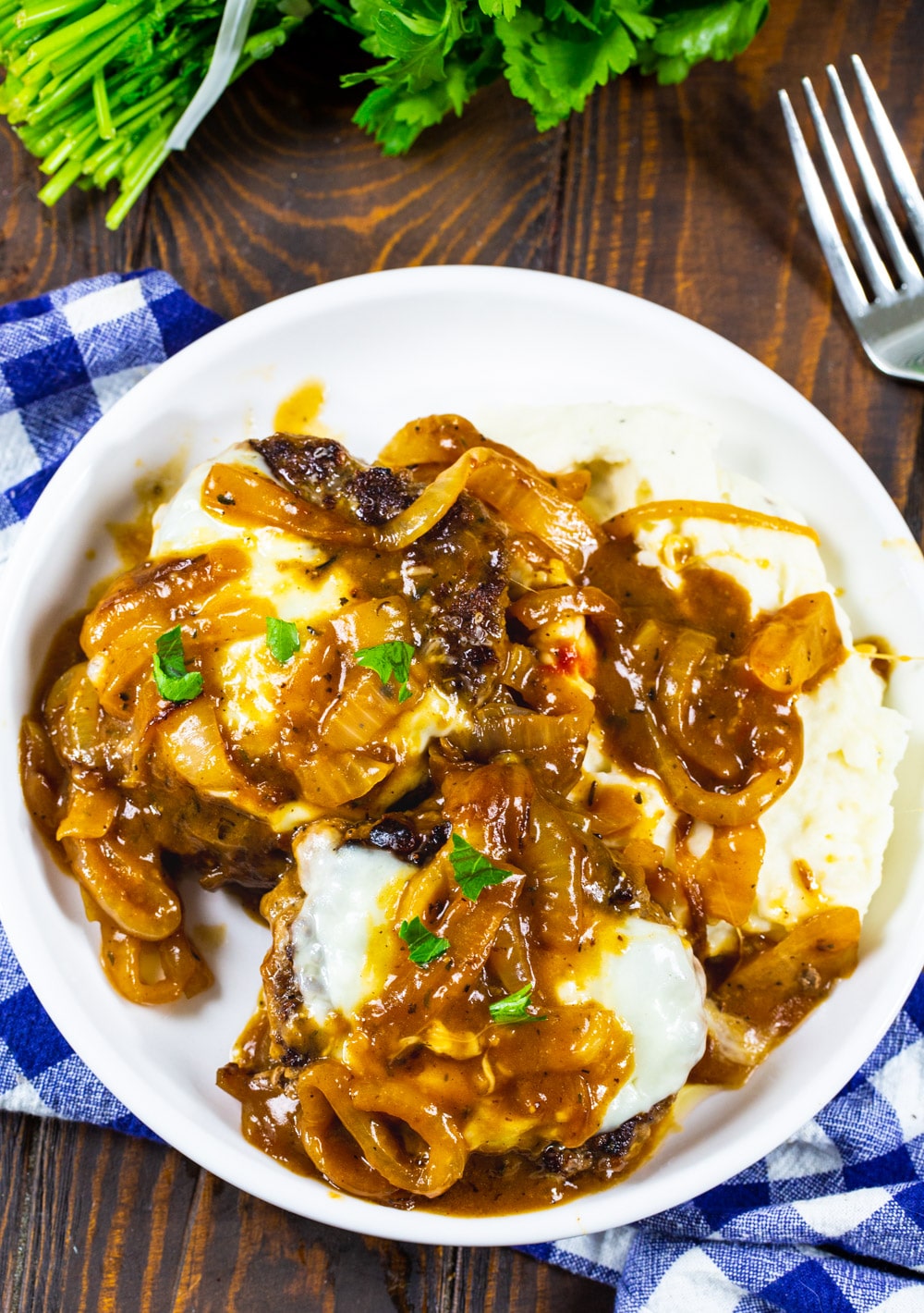 French Onion Salisbury Steak over mashed potatoes on a plate.