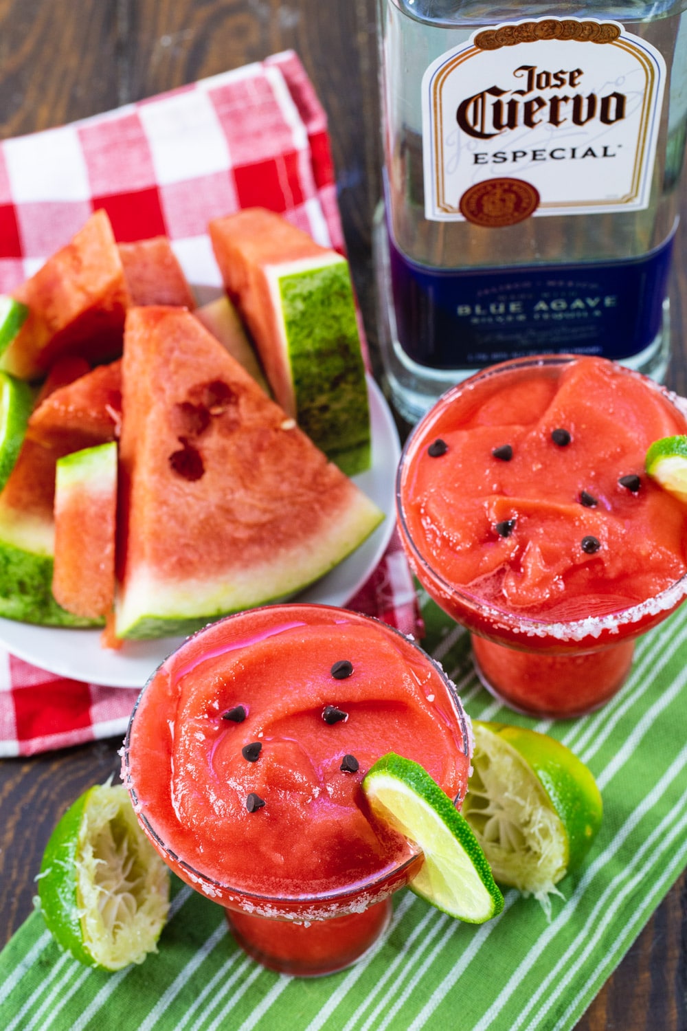 Two Watermelon Margaritas, plate of watermelon, and bottle of tequila.