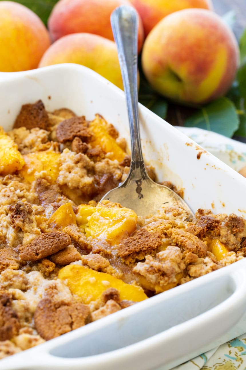 Peach Gingersnap Crisp in white baking dish with serving spoon.