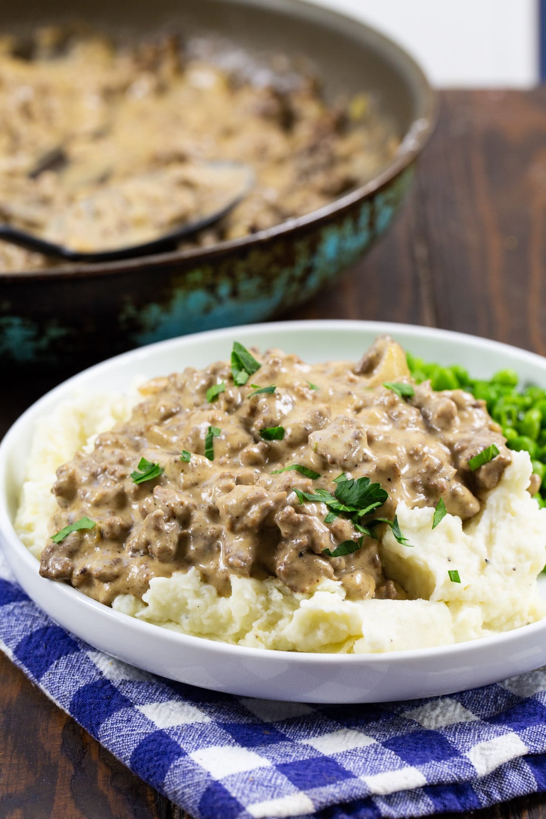 Easy Hamburger Gravy dished up on a plate with skillet in background.