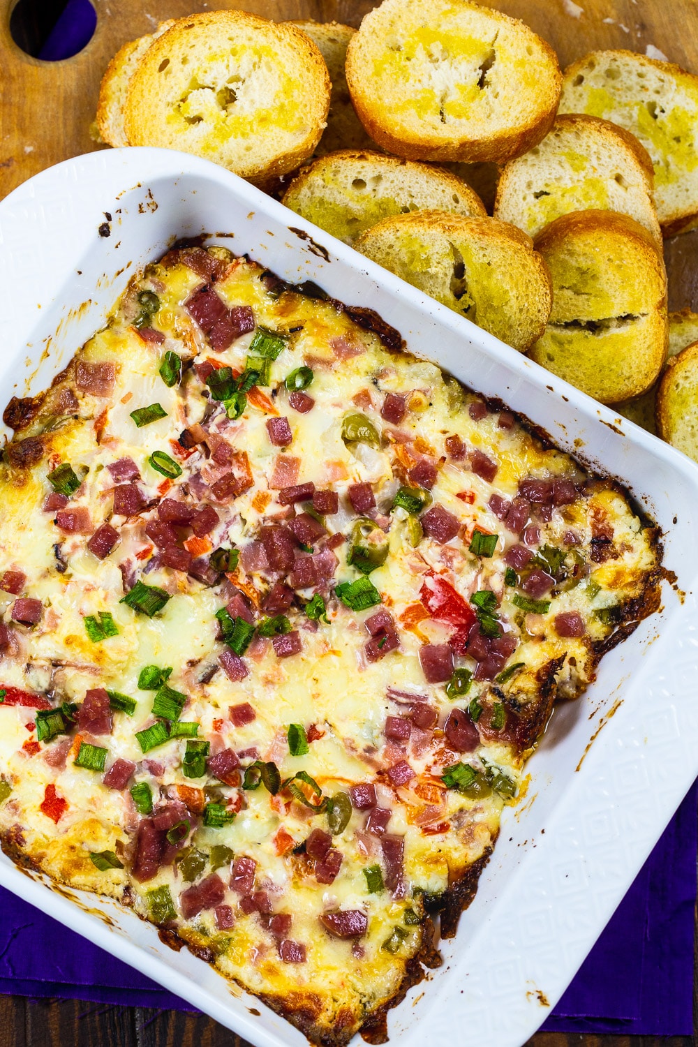 Muffaletta-Style Dip in a baking dish surrounded with baguette slices.