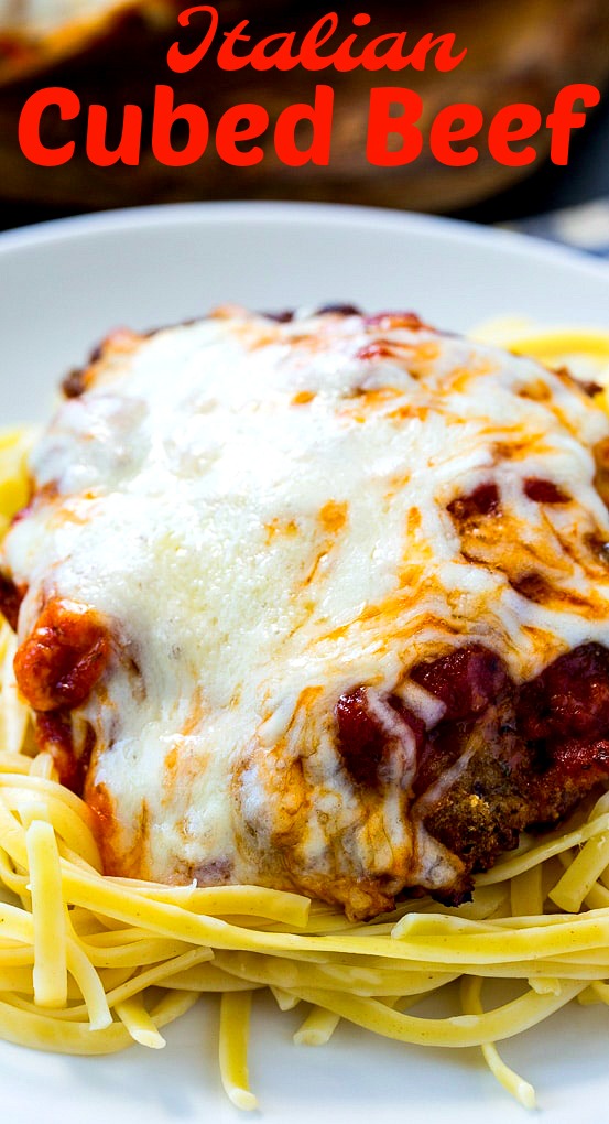 Close-up of Cubed Beef coveered with cheese on spaghetti.