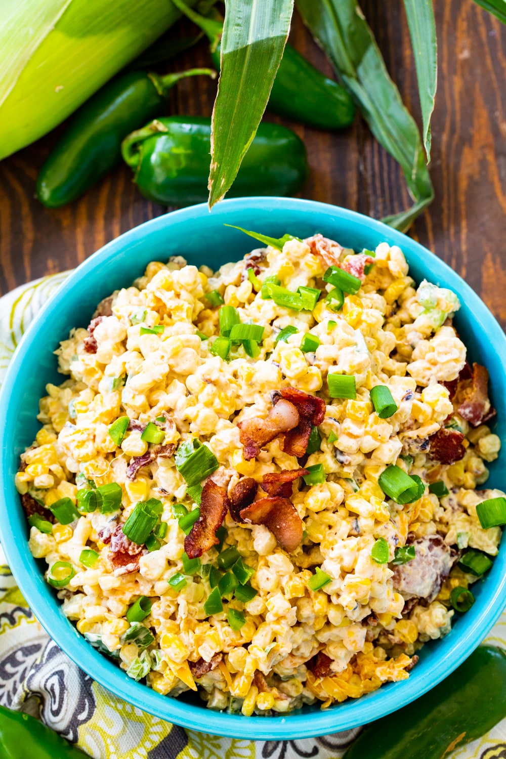 Corn Salad in a blue bowl with ears of corn next to it.