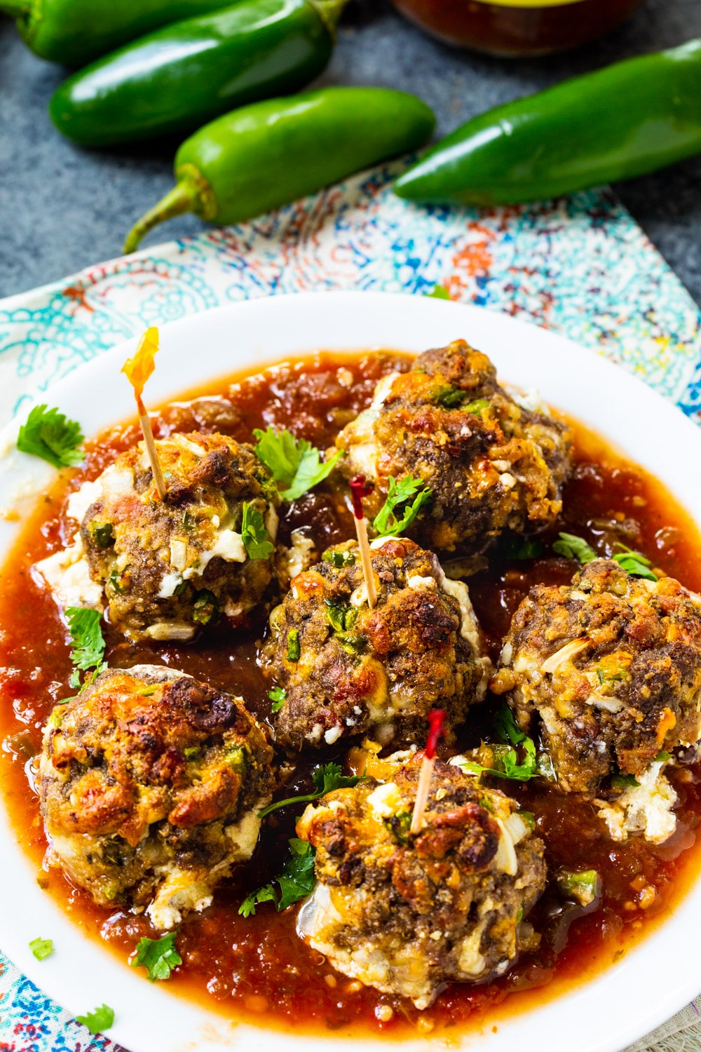 Plate full of Jalapeno Popper Meatballs with fresh jalapenos next to it.