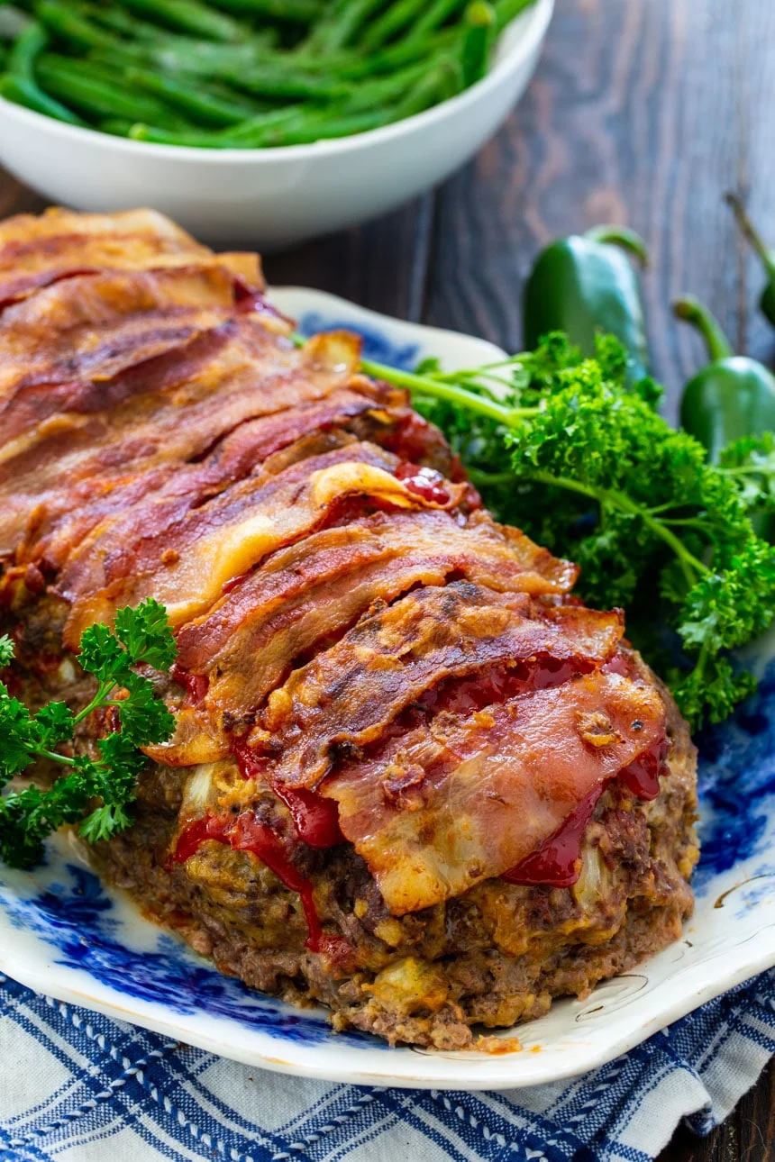 Jalapeno Popper Meatloaf on a plate with fresh parsley and green beans in the background.