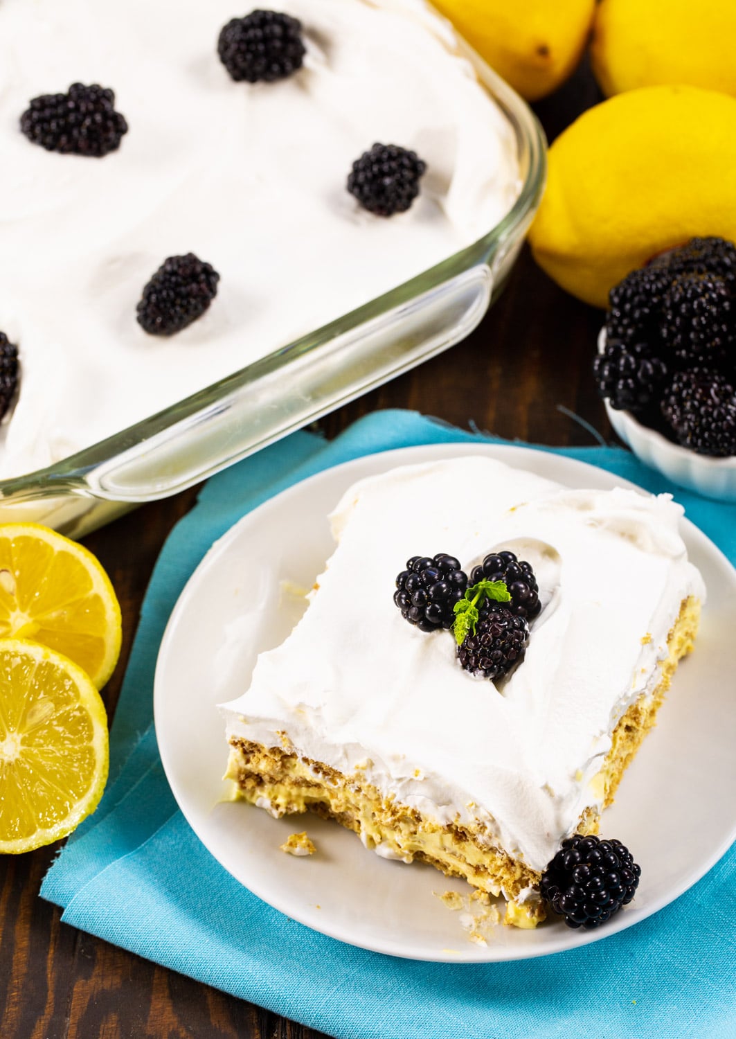 Slice of Icebox Cake on a plate surrounded by lemons and rest of the cake.