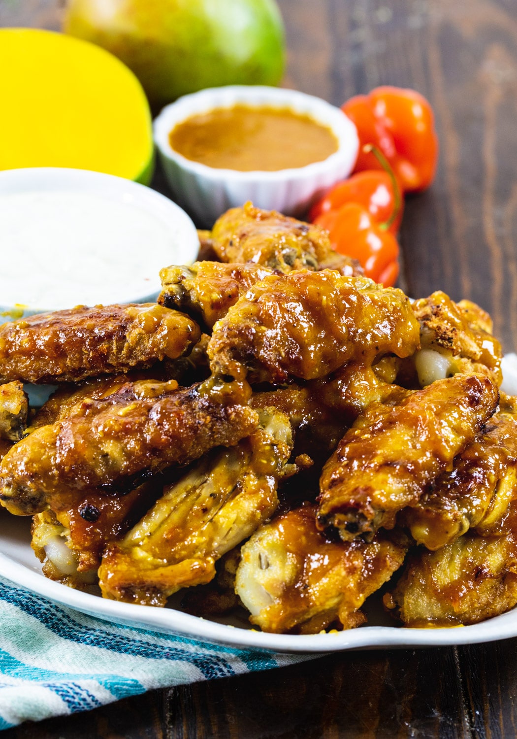 Mango Habanero Chicken Wings on plate with mango and peppers in background.