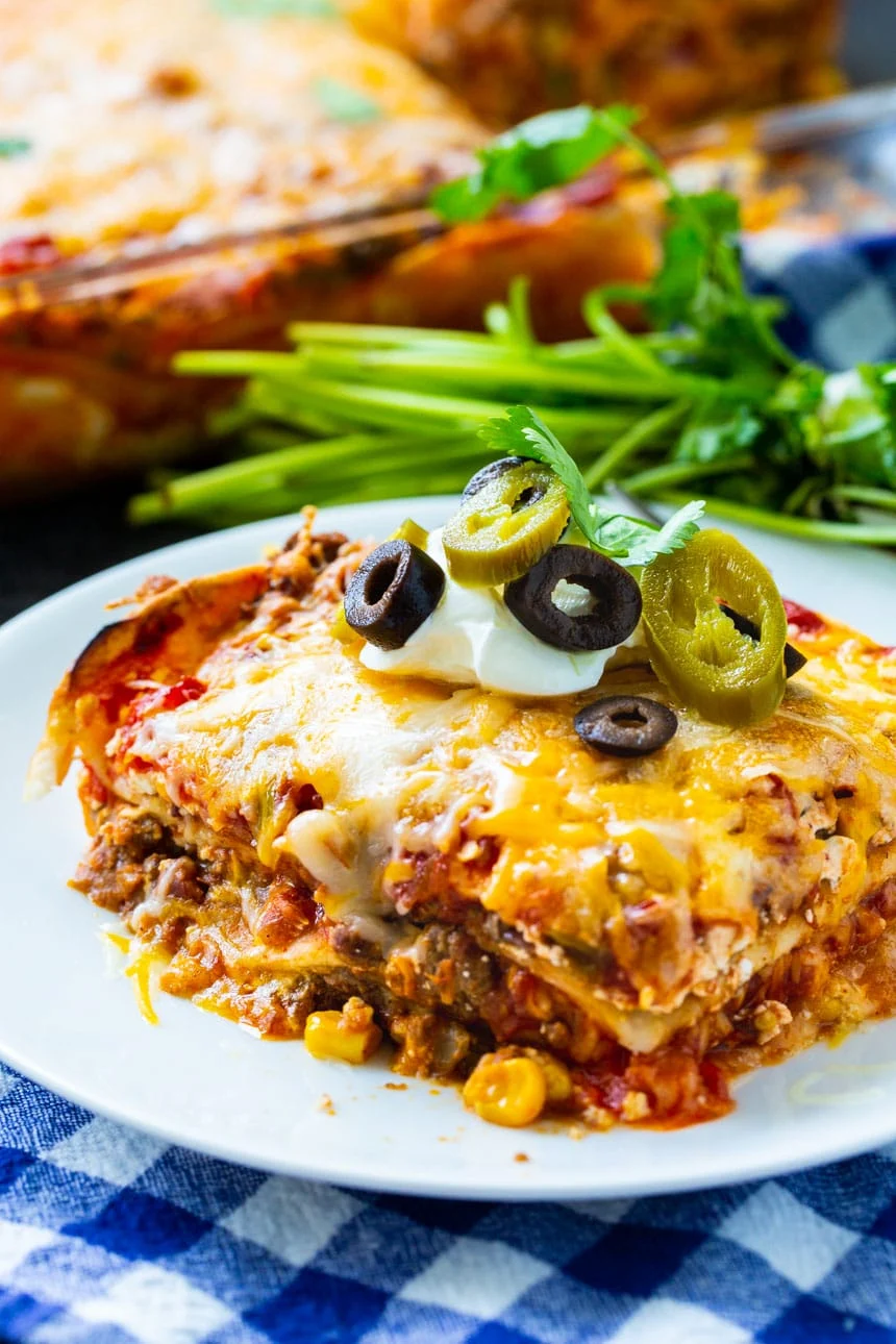 Lasagna on a plate with bunch of lasagna in background.