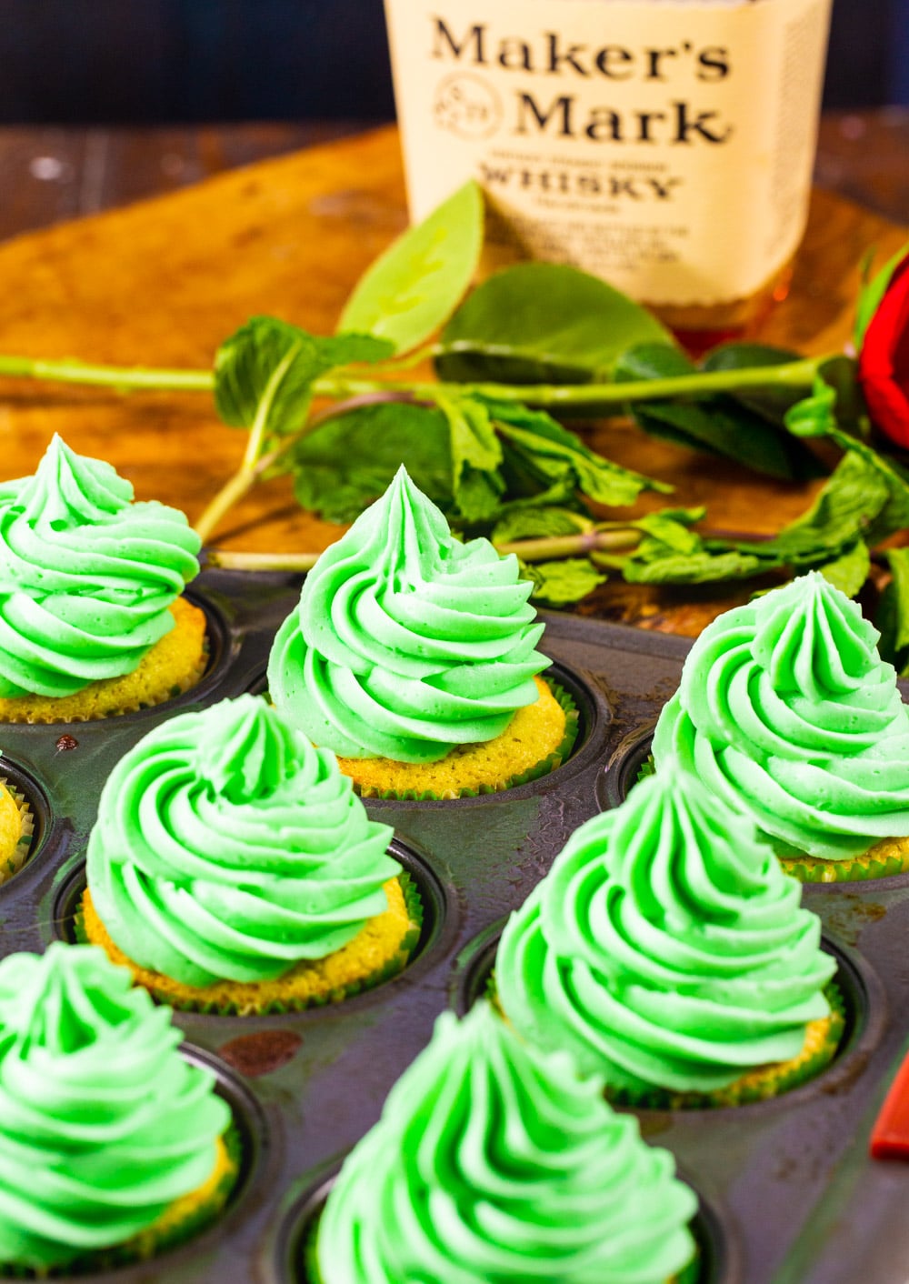 Cupcakes in cupcake pan with a bottle of bourbon.