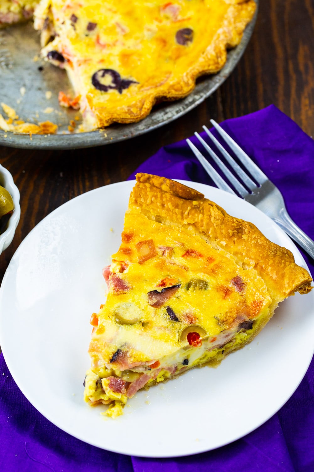 Quiche in a pie pan and a slice on a plate.