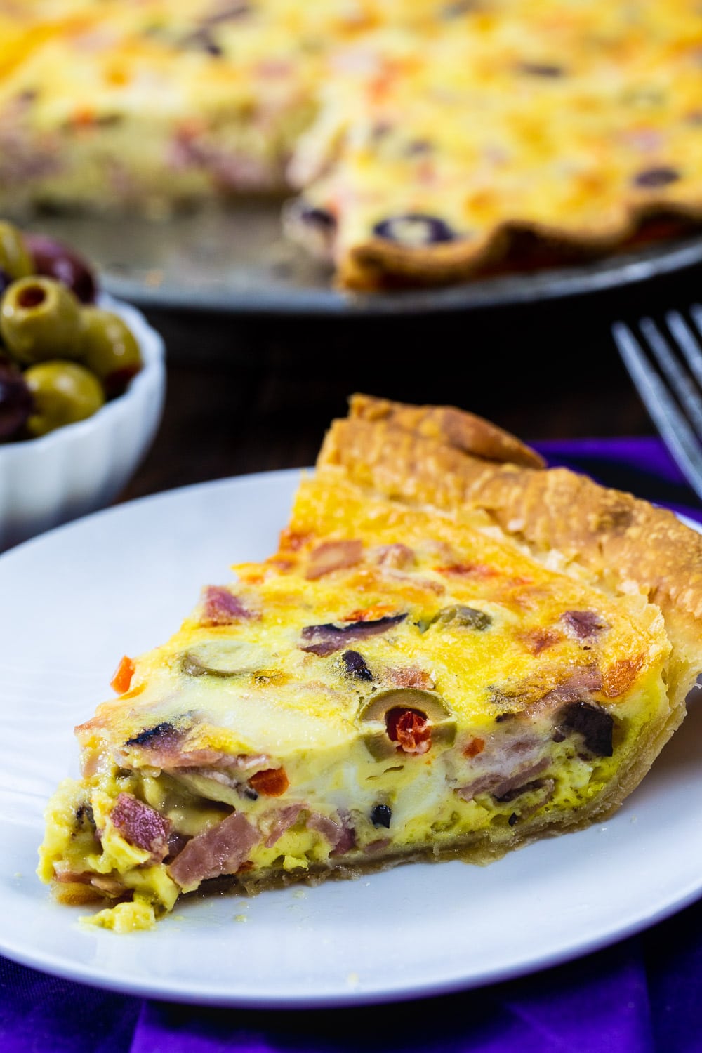 Slice of Muffaletta Quiche on a plate.