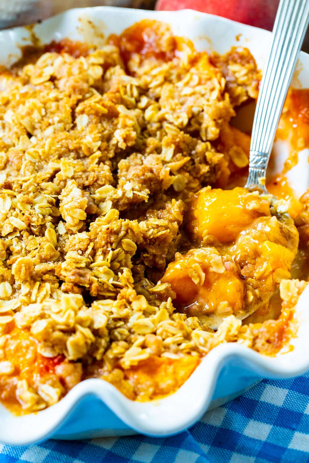 Spoon scooping Peach Crisp out of pie pan.