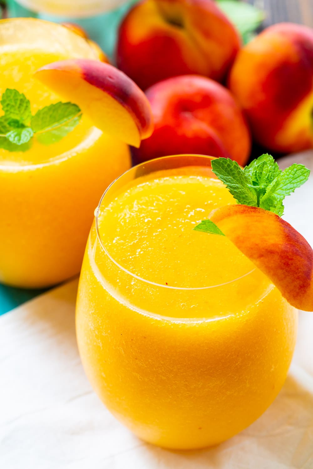 Peach Wine Slushies surrounded by fresh peaches.
