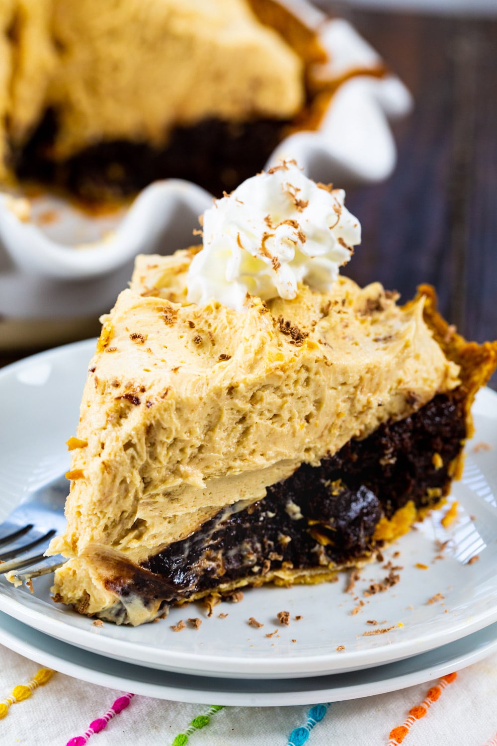 Slice of pie on plate with rest of pie in background.