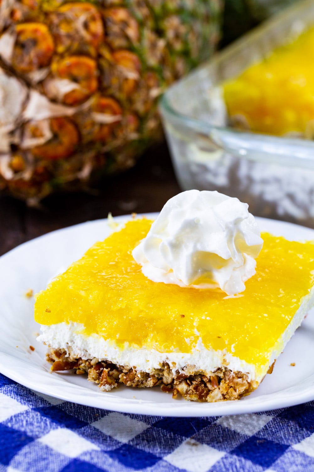 Pineapple Pretzel Salad topped with whipped cream on a plate.