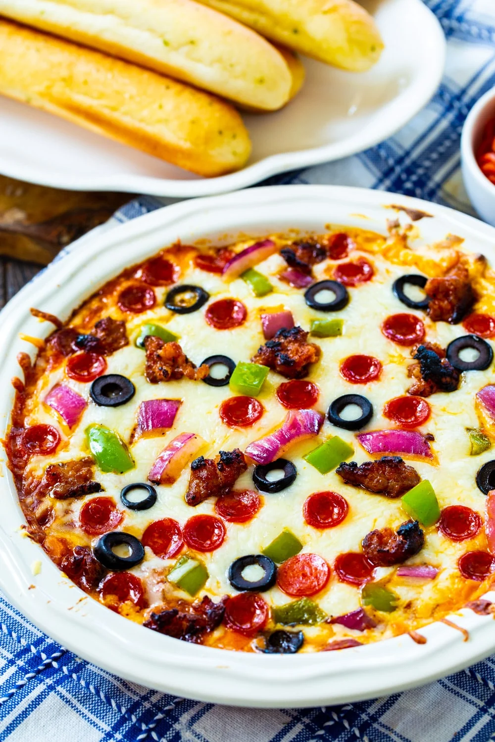 Supreme Pizza Dip with plate of bread sticks.