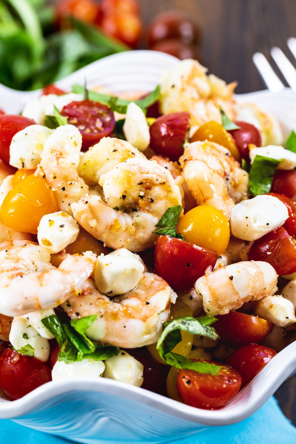 Shrimp Salad with cherry tomatoes and mozzarella balls in white serving bowl.