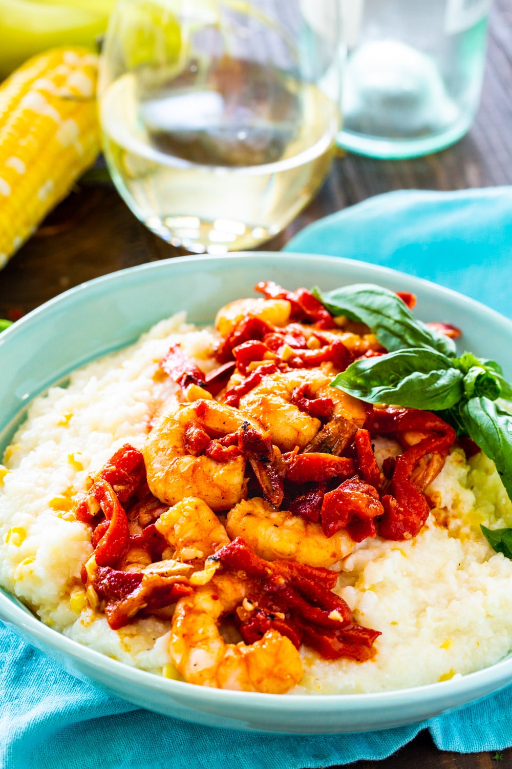 Shrimp and Goat Cheese Grits with Roasted Red Pepper Sauce in a bowl with a glass of wine.