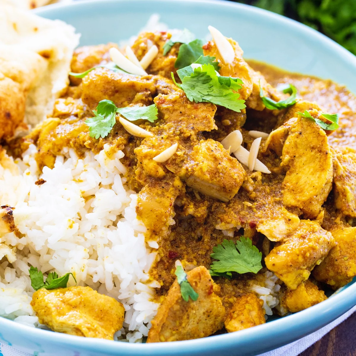 Slow Cooker Chicken Korma over rice in a blue bowl.