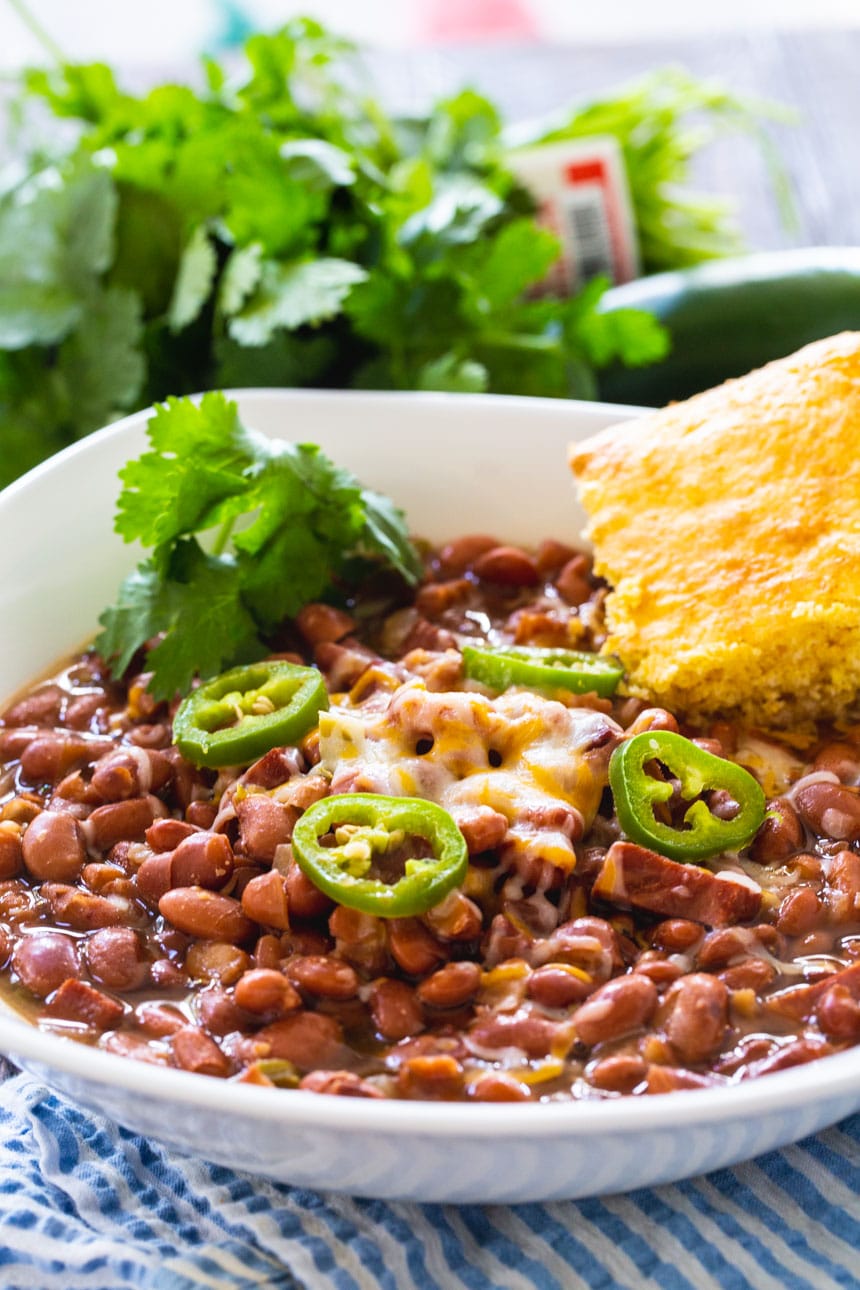 Slow Cooker SPicy Pinto Beans in a white bowl with cornbread.