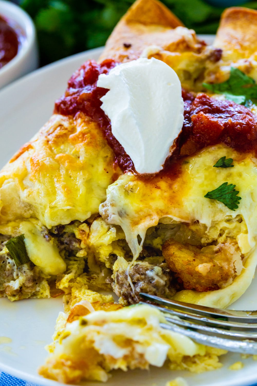 Fork cutting into Spicy Sausage Breakfast Enchilada